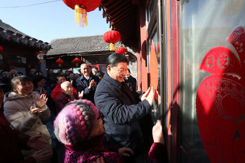 2019年2月1日上午，習(xí)近平在北京前門東區(qū)草廠四條胡同32號(hào)院，高興地拿起一幅“?！弊?，親自貼到門上，給這里的老街坊們拜年。新華社記者 鞠鵬 攝