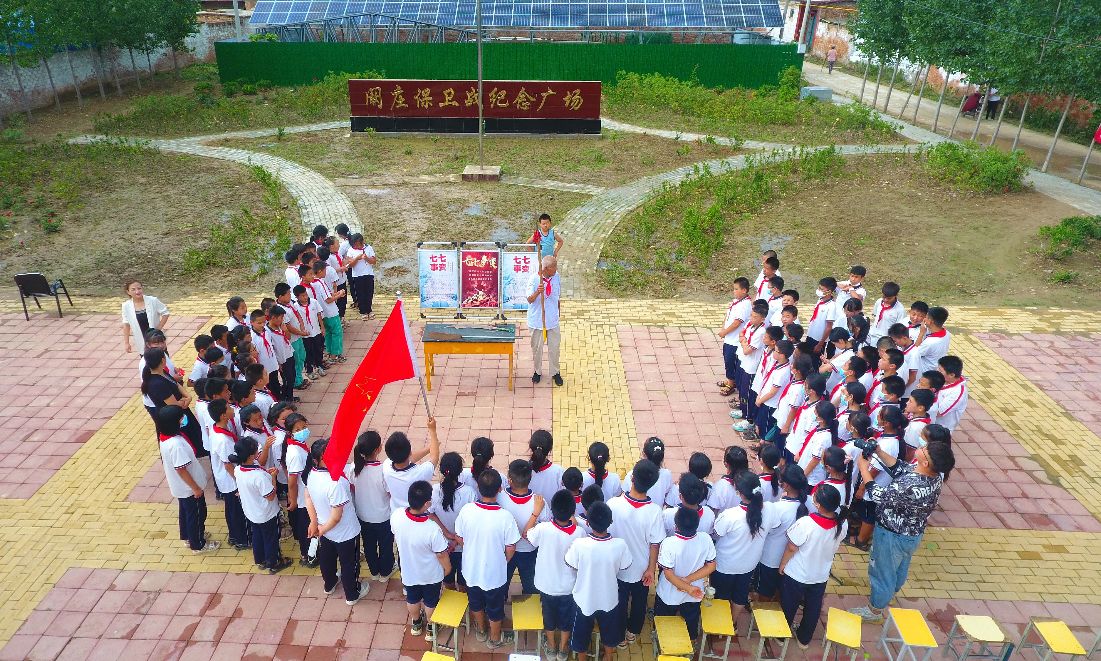 2022年7月6日，山東省聊城市，在茌平區(qū)菜屯鎮(zhèn)闞莊村的闞莊保衛(wèi)戰(zhàn)紀念廣場，闞莊保衛(wèi)戰(zhàn)親歷者王光木老人，為小學生們講述抗戰(zhàn)故事，展示大刀、長矛。